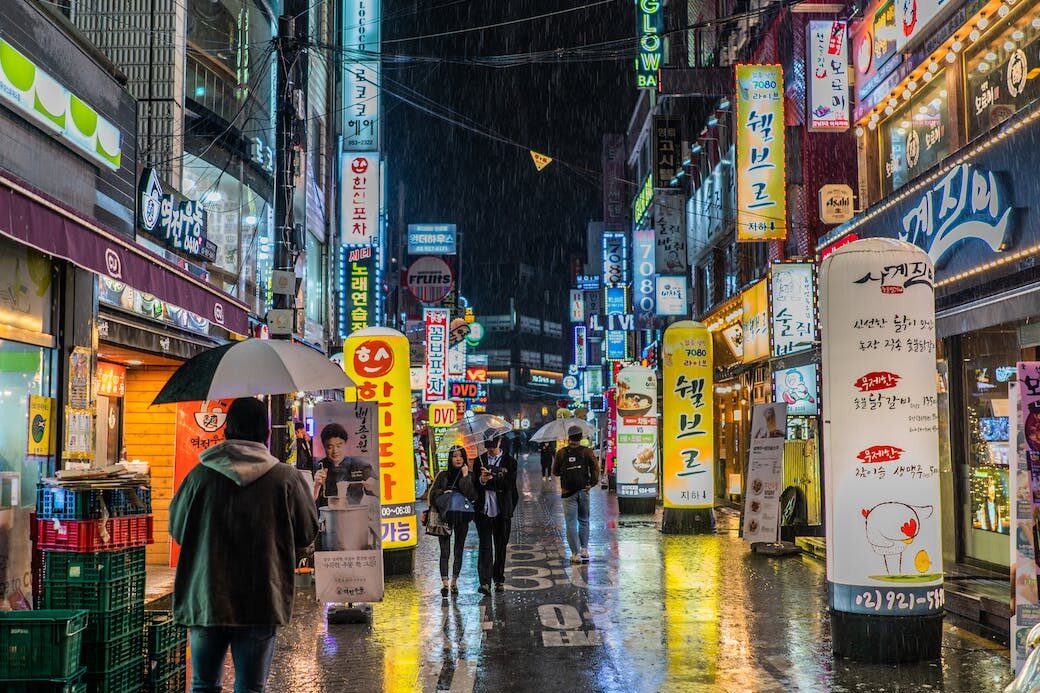 person wearing black jacket holding black umbrella walking on street