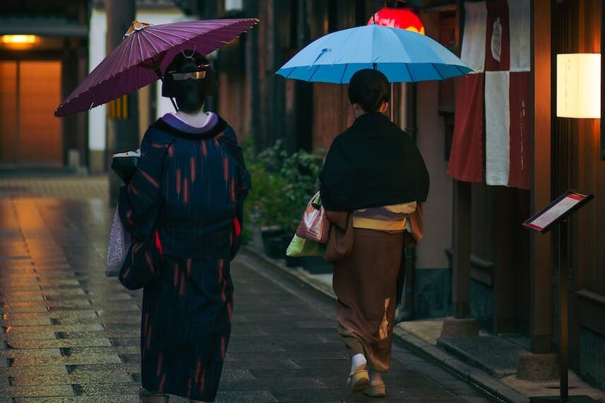 woman in traditional outfits and umbrellas walking together